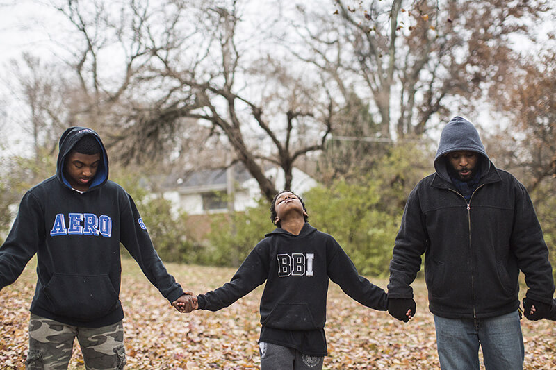 Members of the Village, a community mentoring program to offer support to young black men, hold hands as they pray in Ferguson, Mo.