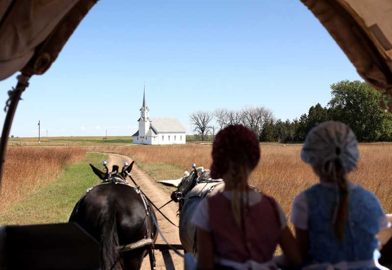 From left: Grace Steinbart, 5, and her sister Elisabeth, 7, helped to drive the mule team as they rode in a covered wagon across the prairie at the Ingalls Homestead.