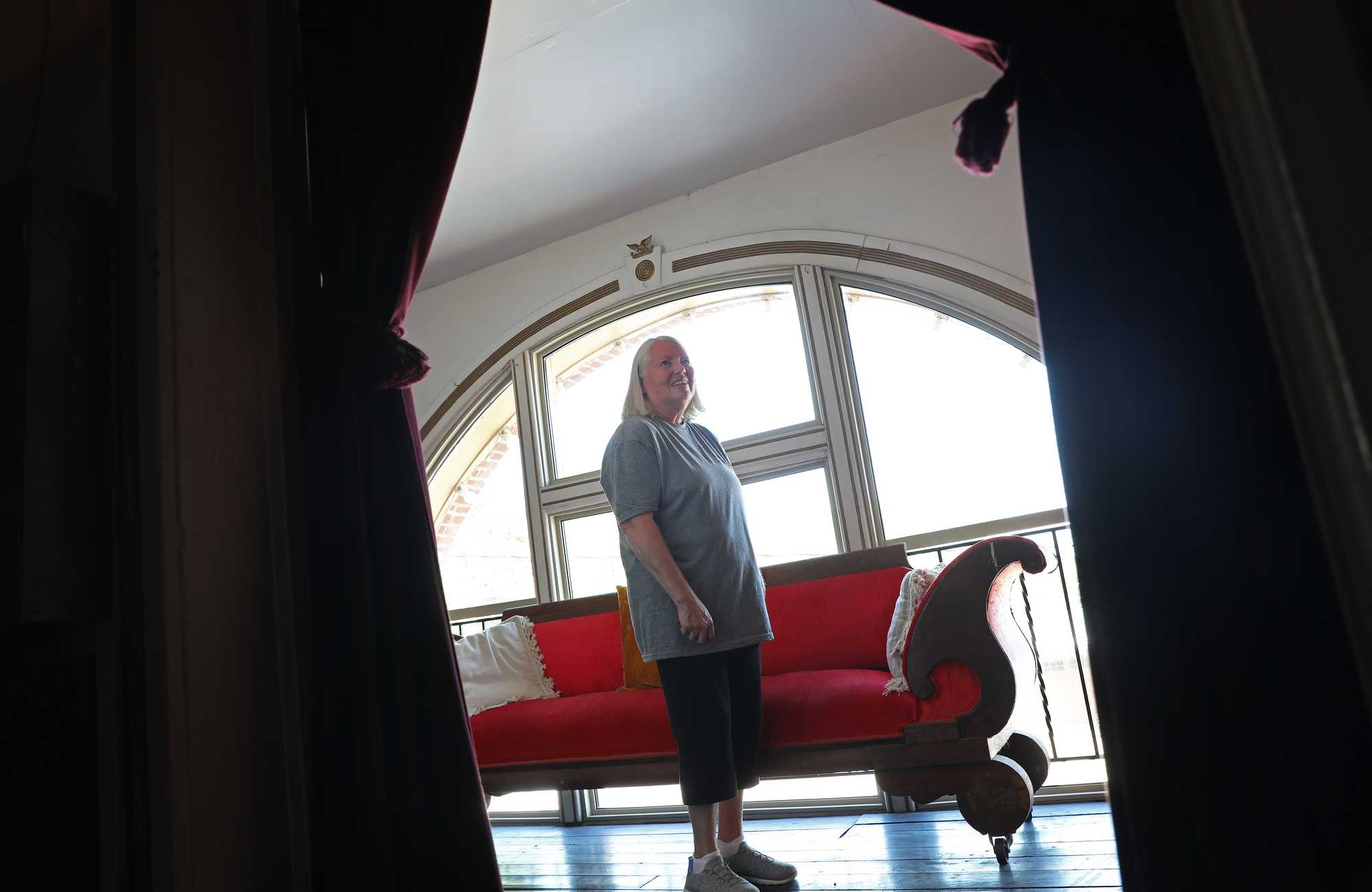 Judy Striegel, standing near a roughly 100-year-old settee in the balcony, is working to restore the old opera house.
