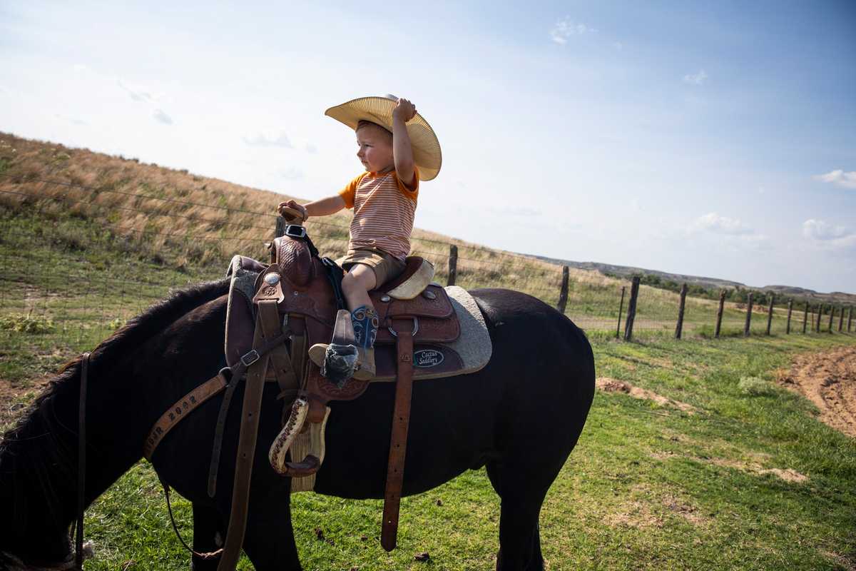 Two-year-old Beck Booze adjusted his cowboy hat while riding a horse around his grandfather’s ranch.