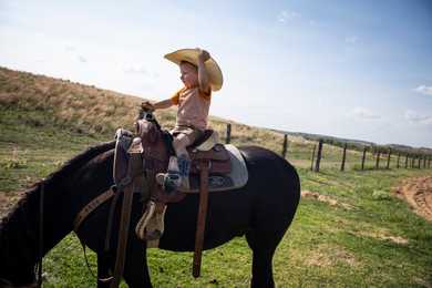 Beck Booze, 2, adjusts his cowboy hat while riding his horse around his grandfather’s  ranch in Miami, Texas. 