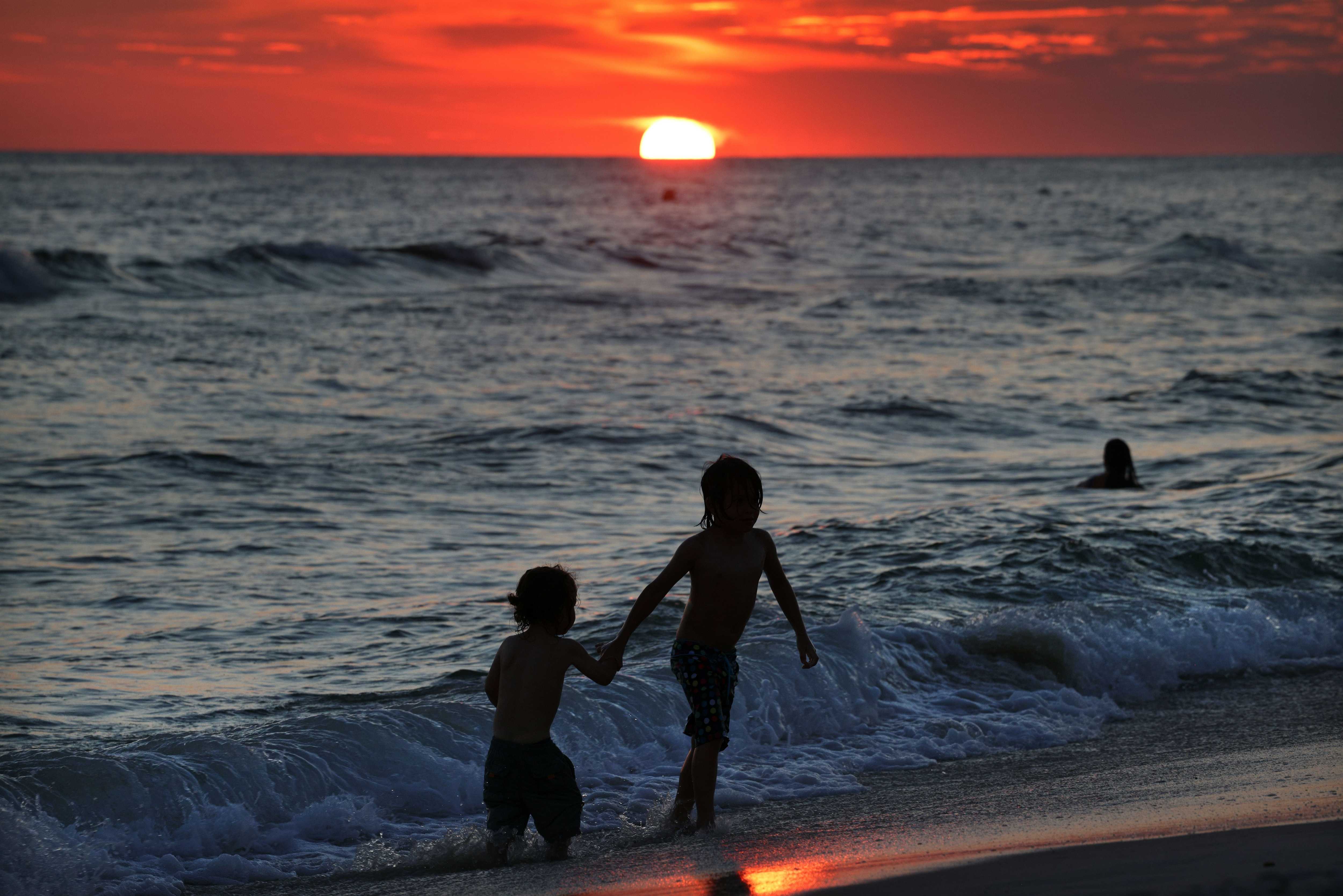 A pair of children walked in the water as the sun sets on the Gulf of Mexico in Panama City Beach, Fla., on Sept. 17.