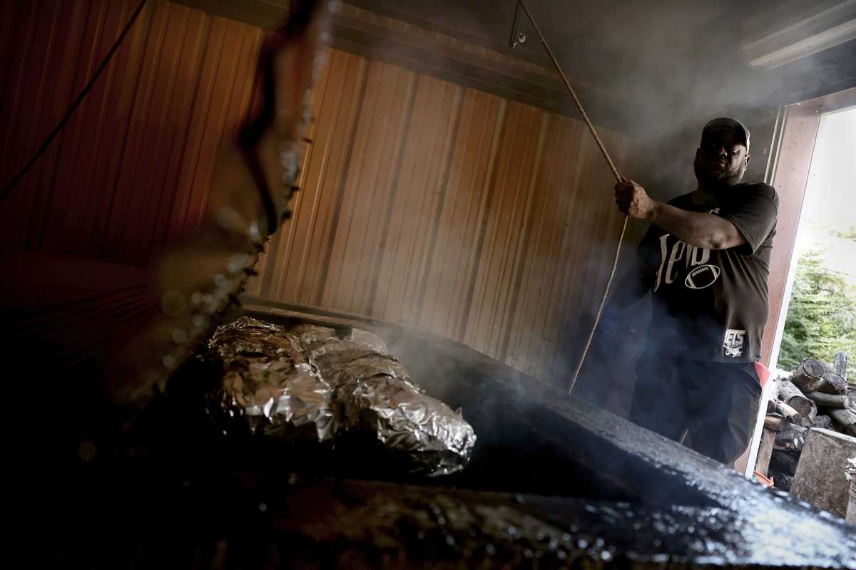 James H. Jones Jr. pulled open the charred tin plank that covers the concrete smoker that maintains the heat at 400-plus degrees.