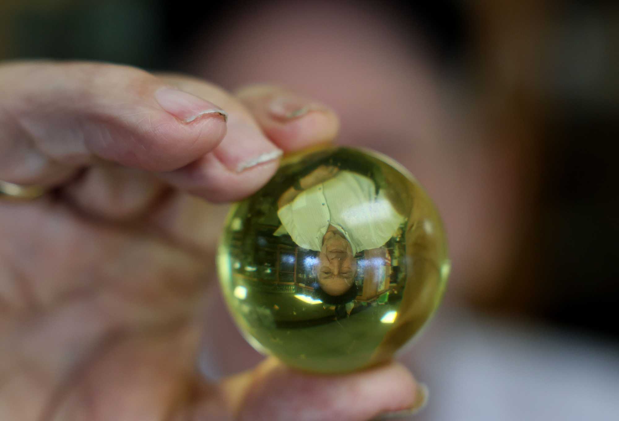 Batterton's reflection appeared upside down as he held out a marble from his collection. 