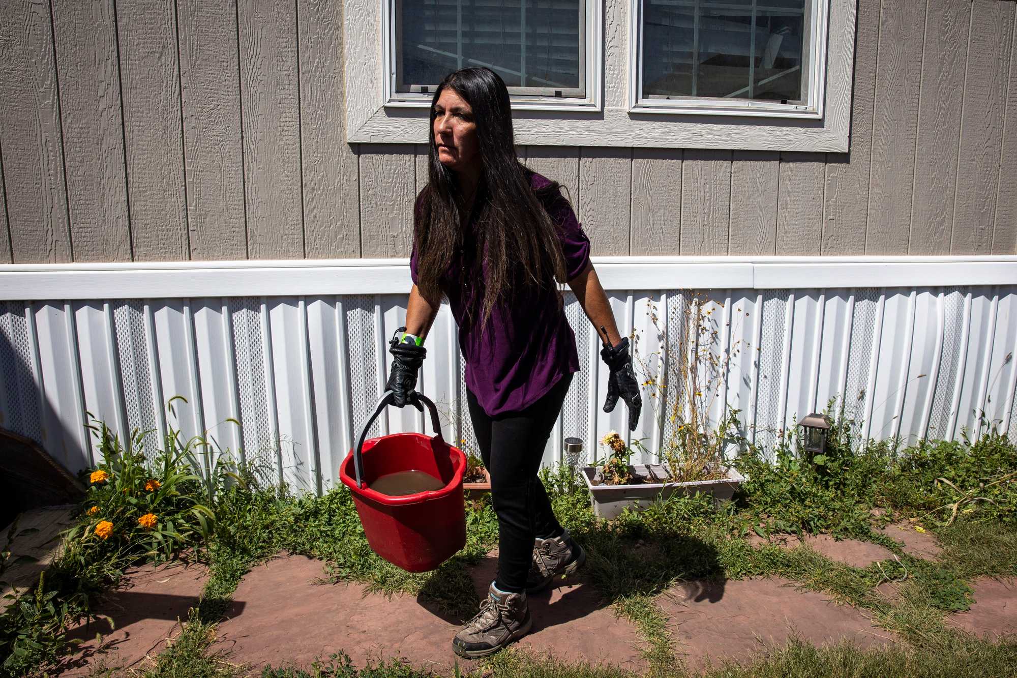 Adelina Paiz-Vaughn waters her garden with buckets that she filled up from the river near her home. Ash and soot from the fire poisoned the local water supply, leaving the area facing further water restrictions.
