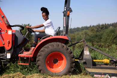 Nyema Clark, of Nurturing Roots learns how to drive a tractor for the first time on Small Axe Farm in Redmond, Wash.