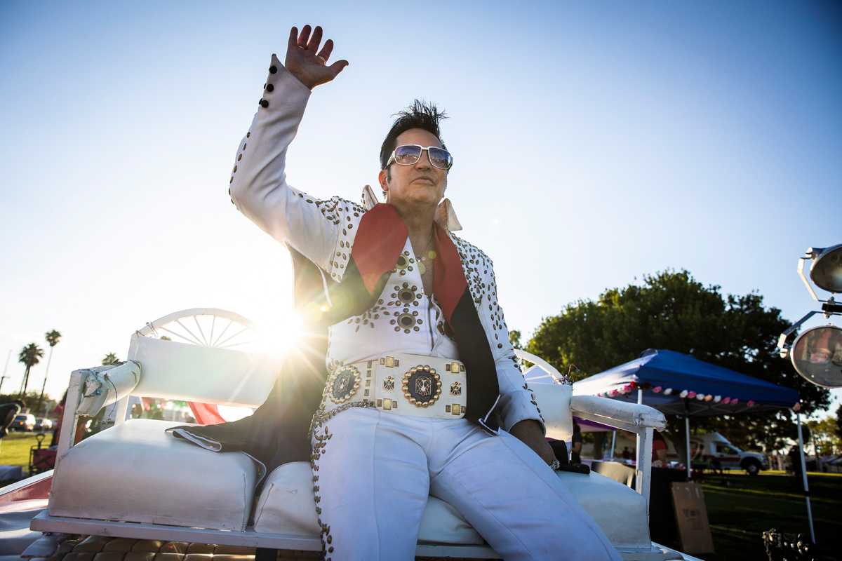Jesse Grice, an Elvis impersonator of over 30 years, waved from atop his pink Cadillac convertible. 

