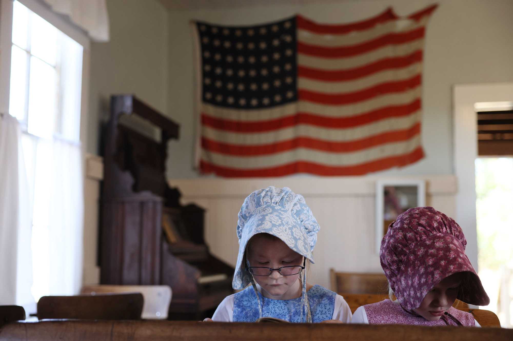Elisabeth (left) and Grace Steinbart read at a desk inside the schoolhouse at the Ingalls Homestead in early September.