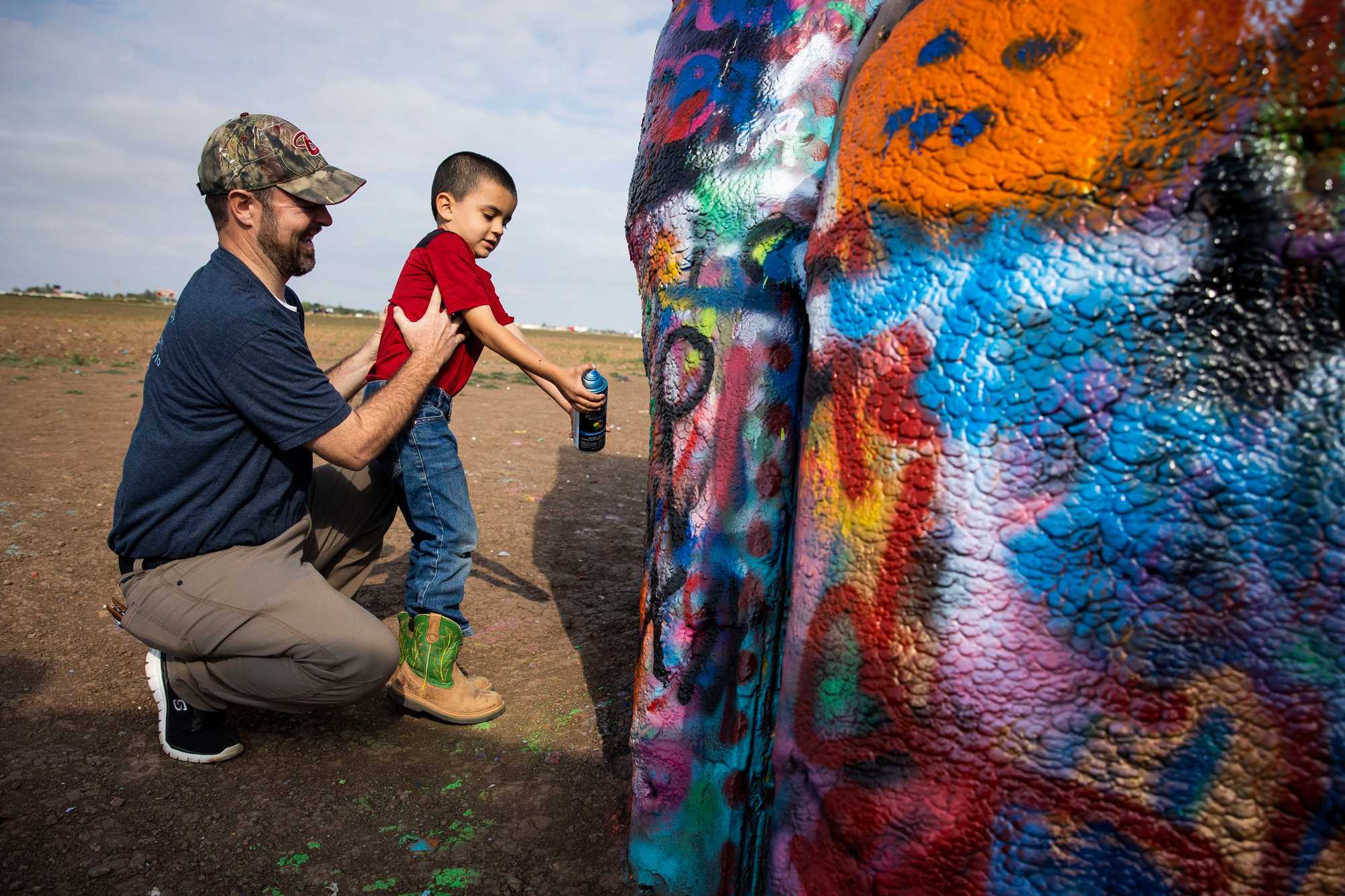 Joel Haynes helped his 5-year-old son, Justus, spray paint a car at Cadillac Ranch during a visit in September. 