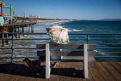 A woman held an umbrella to shade herself from the sun while enjoying the afternoon on the Santa Monica pier in Los Angeles. 