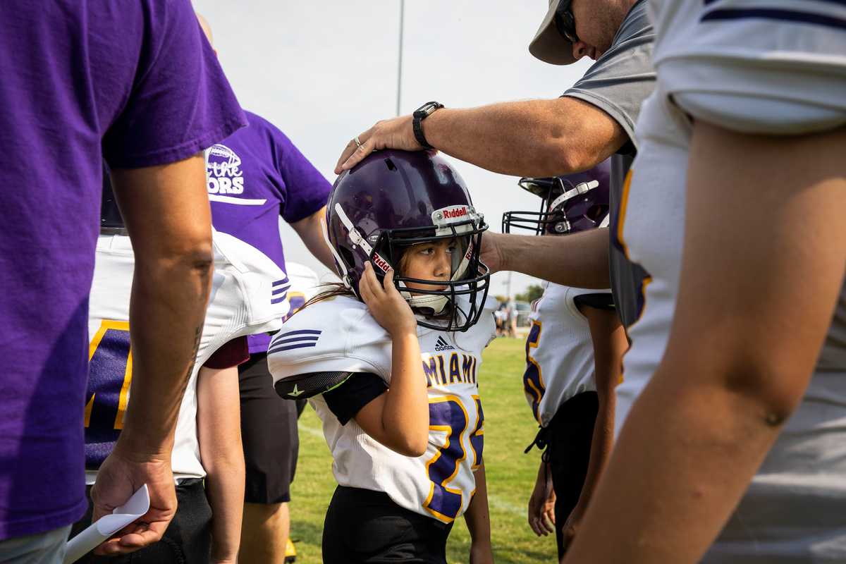 A quick helmet adjustment for Callie John Calvert during her first game for Miami independent school district.