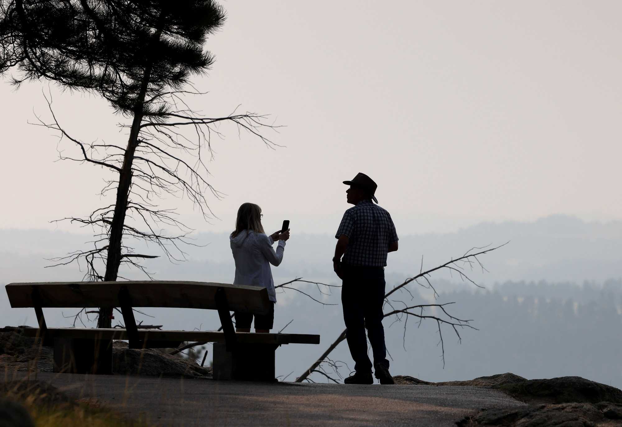 Visitors to Devils Tower turn to take in the smoke from neighboring wildfires that have filled in the valley.