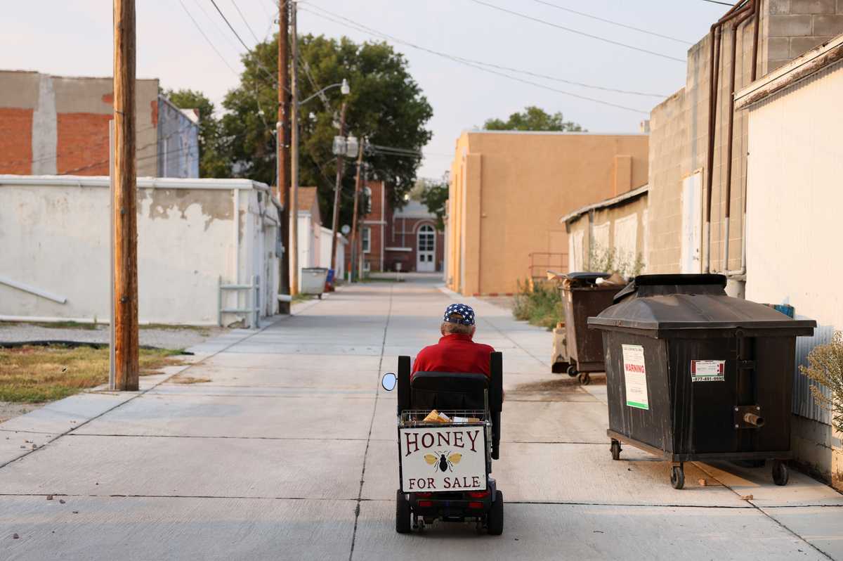 Dewayne Voborny used a scooter to ride through Neligh, Neb., carrying jars of honey with him on Sept 8. Voborny started out as a baker, then worked seasonal agriculture jobs before becoming a school bus driver and finally a honey dealer.