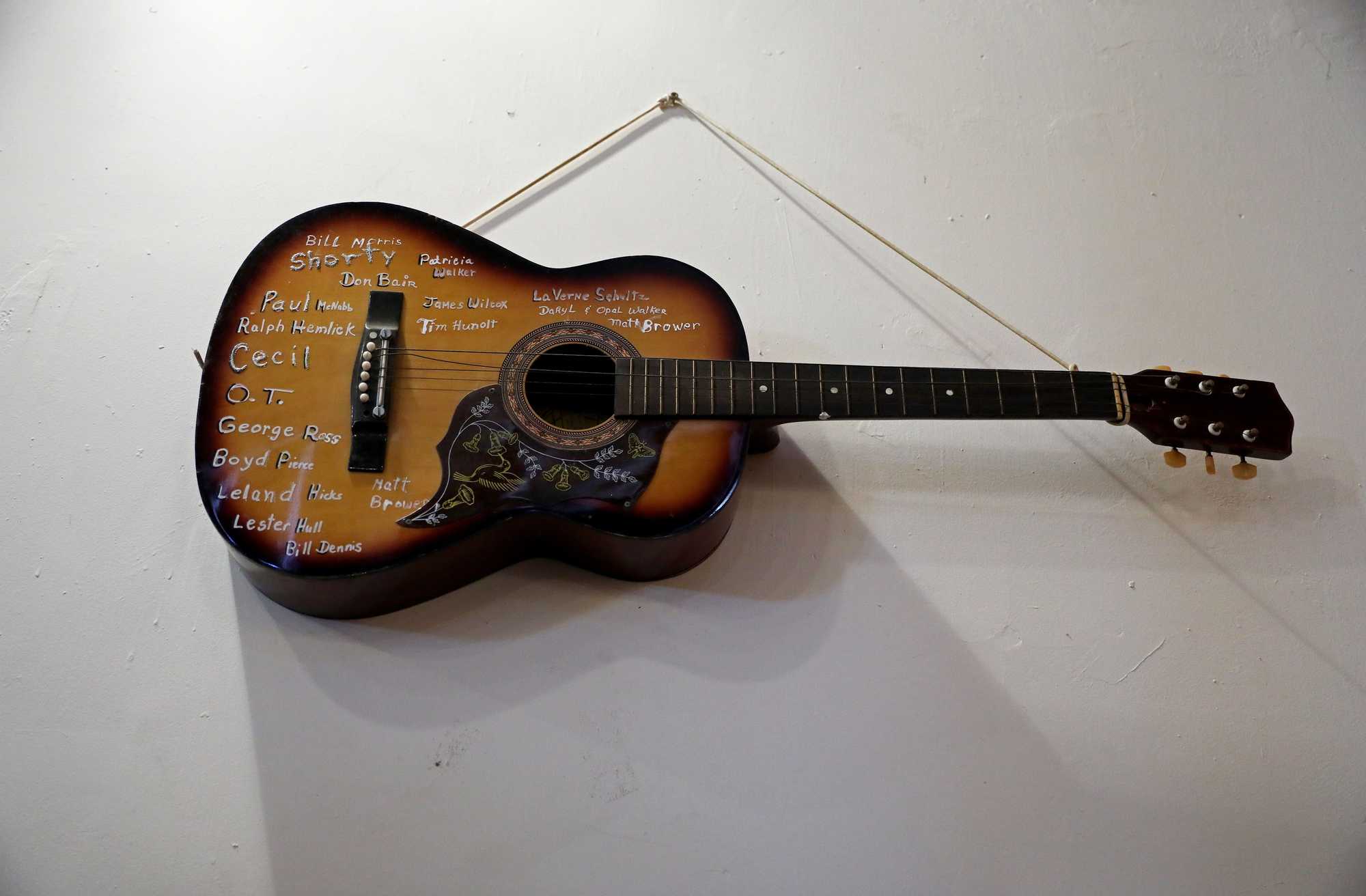 This acoustic guitar hanging at the What Cheer Opera House is marked with the names of performers who have strummed it. 