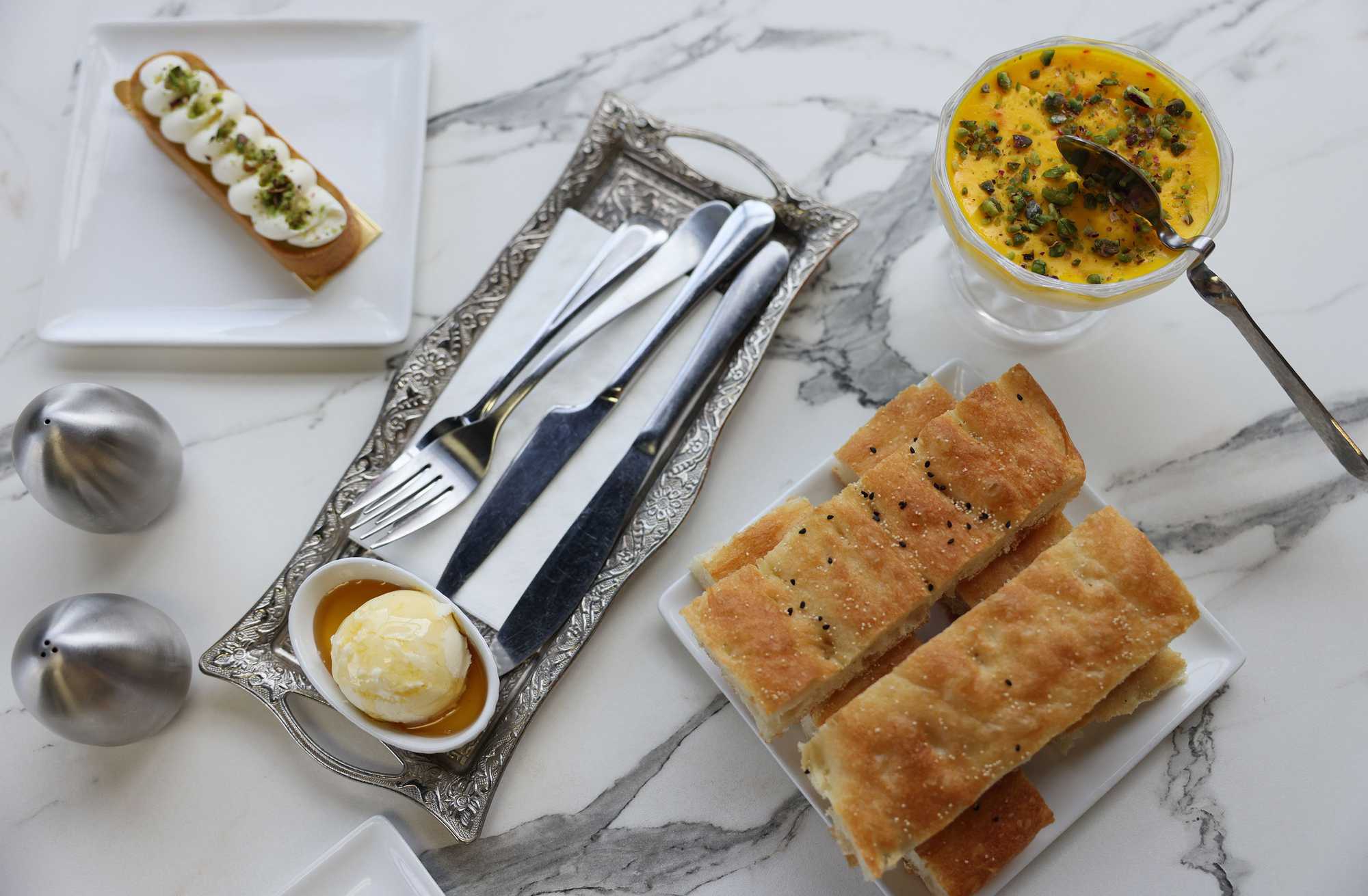 Clockwise from left: The Passionfruit Tart, Saffron Pudding, Afghan Bread and Honey Butter served up at Sunshine Spice Bakery & Cafe. 