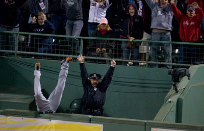 Torii Hunter falls into the bullpen trying to catch a home run by David Ortiz. A security guard next to him celebrates with arms raised.