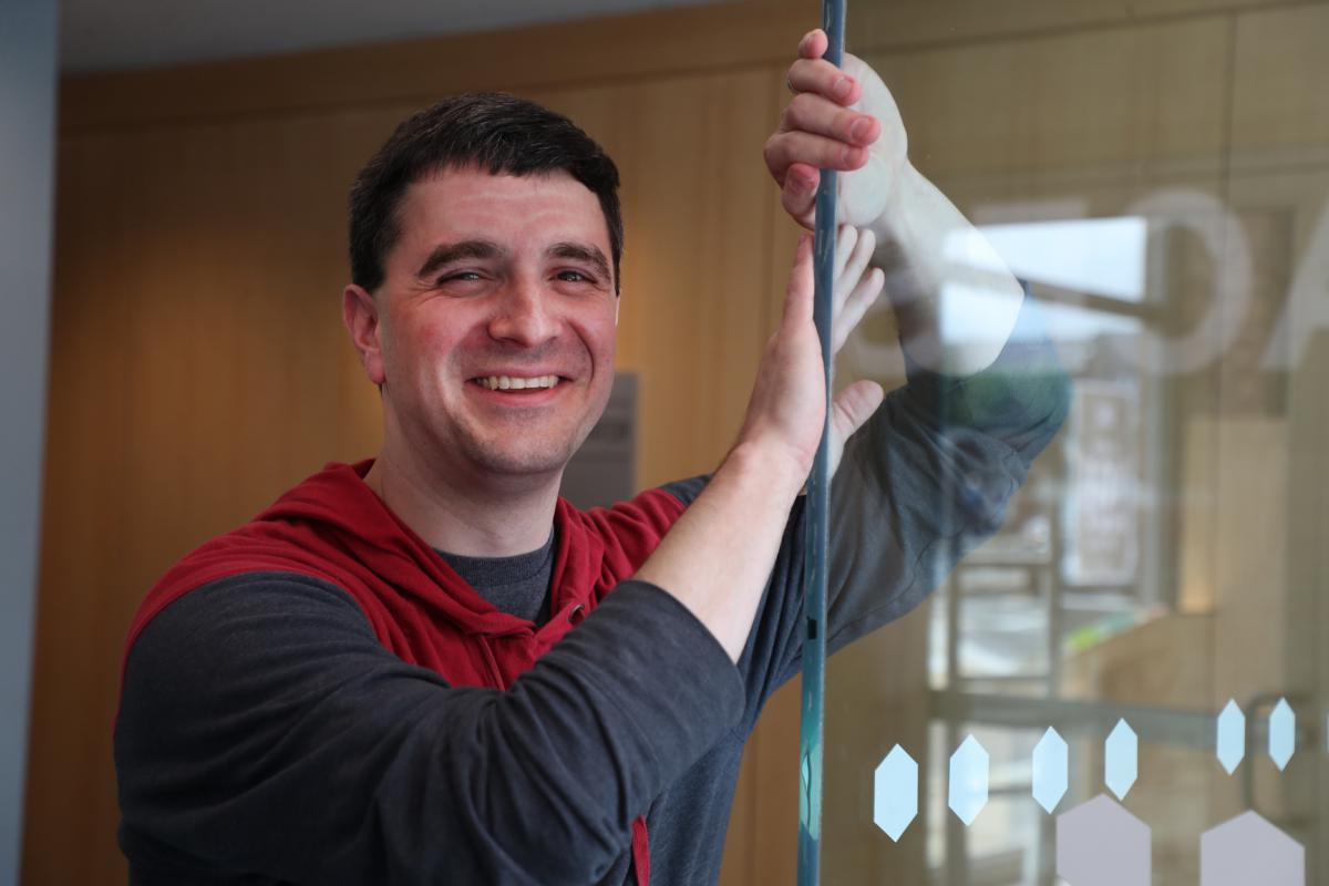 Baseball analytics expert Jeff Stern smiling while standing next to a glass door at the TruMedia office