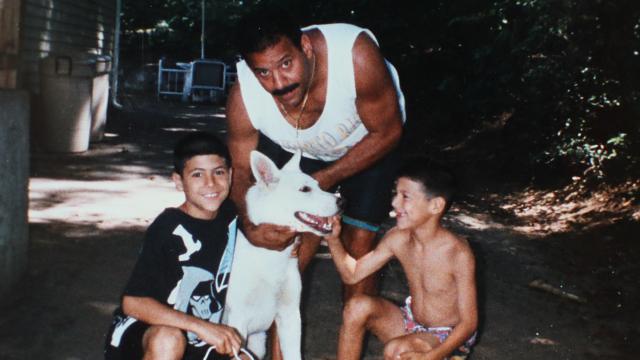 Aaron Hernandez pets a dog alongside his brother and father in a family photo