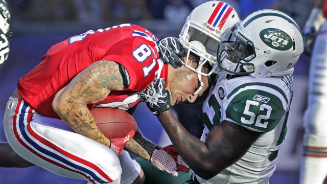Former New England Patriot Aaron Hernandez colliding headfirst with an opposing player. His helmet is almost off his head